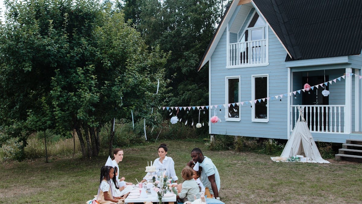 A diverse group enjoying a garden party around a table outdoors.